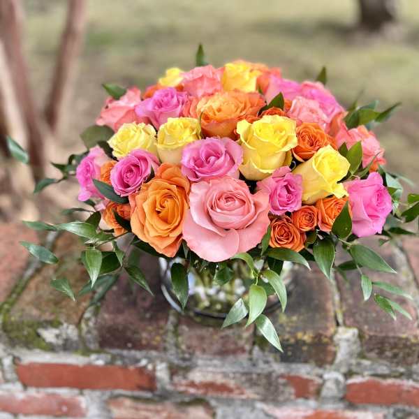 Bouquet of pink, yellow, and orange roses in a glass vase