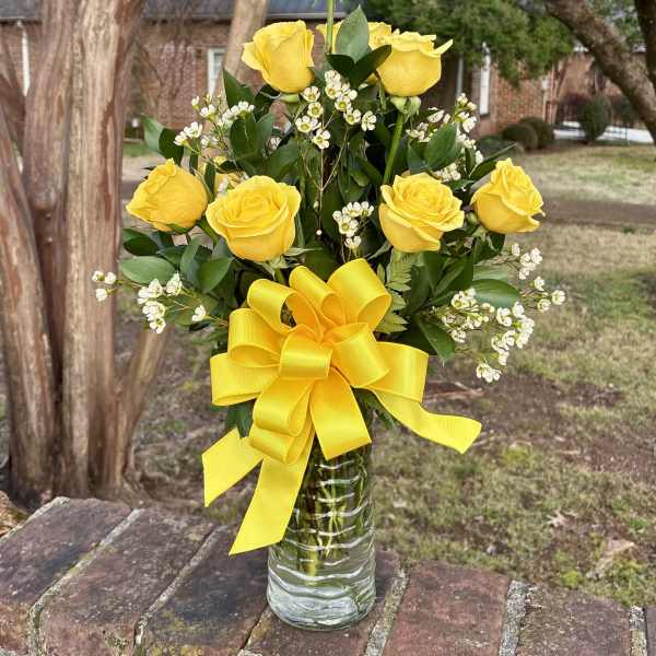 Yellow roses in a glass vase with a large yellow bow