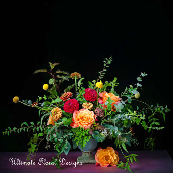 Orange and pink floral arrangement in a blue vase with trailing greenery