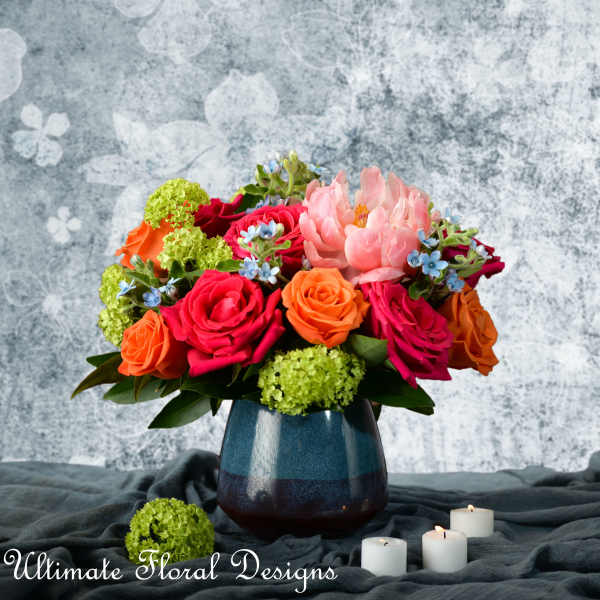 Mixed bouquet of roses and peonies in a blue vase with candles