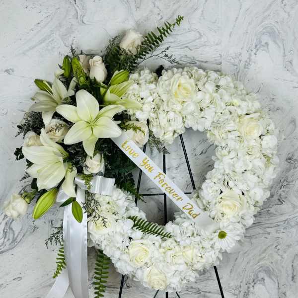 White floral funeral wreath on a black stand with a ribbon