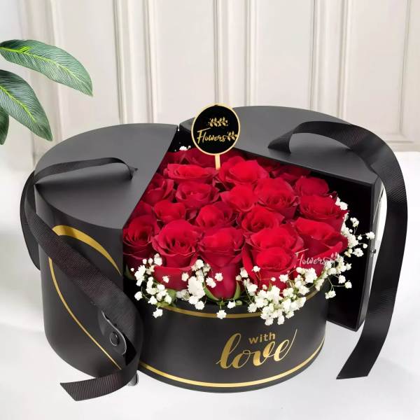 Red roses in a black round gift box with a ribbon handle