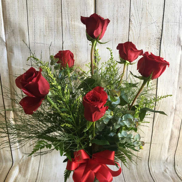 Red roses in a clear glass vase with a red ribbon