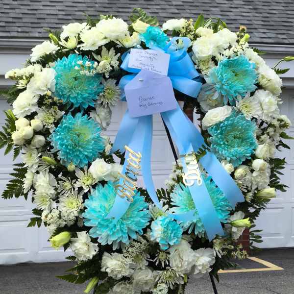 Large white and turquoise funeral wreath with blue ribbons