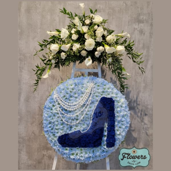 Blue floral standing spray with a high-heel shoe design and white flowers on top