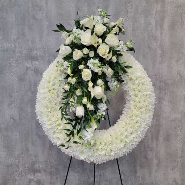 White floral funeral wreath with roses and lilies on a stand