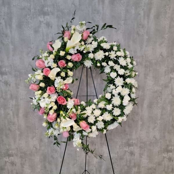 Large floral wreath with pink and white flowers on a black stand