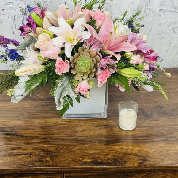 Pink and white mixed flower arrangement in a square glass vase