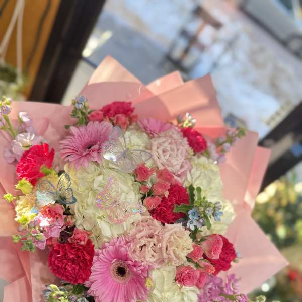 Pink and white mixed bouquet wrapped in pink paper with butterfly picks