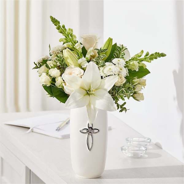 White floral arrangement in a tall vase with a cross emblem