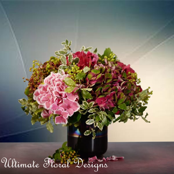 Pink hydrangea arrangement in a black vase with variegated greenery