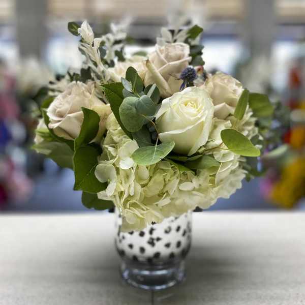 White roses and hydrangeas in a spotted glass vase