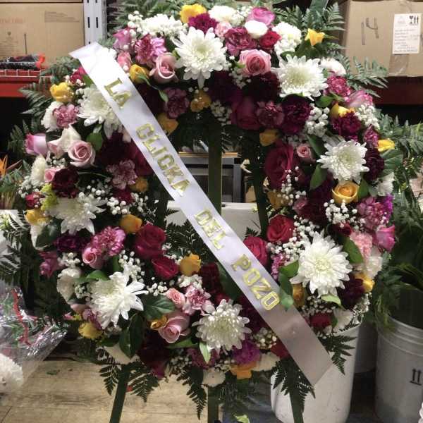 Large floral funeral wreath with pink, white, yellow, and burgundy flowers