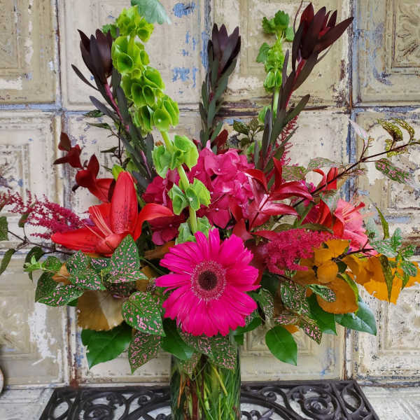 Bright mixed bouquet in a clear glass vase with pink and red blooms
