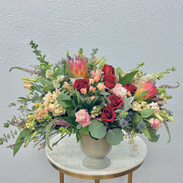 Mixed bouquet of red and pink roses with tropical blooms in a vase