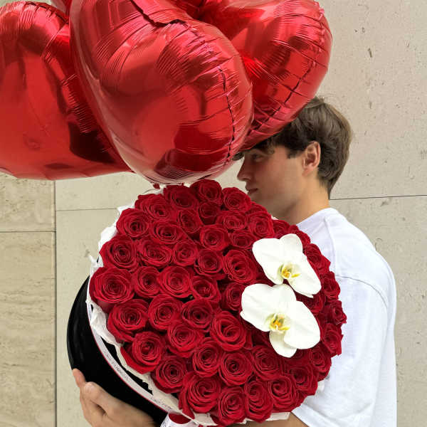 Heart-shaped red balloon bouquet with a round red rose arrangement and white orchids