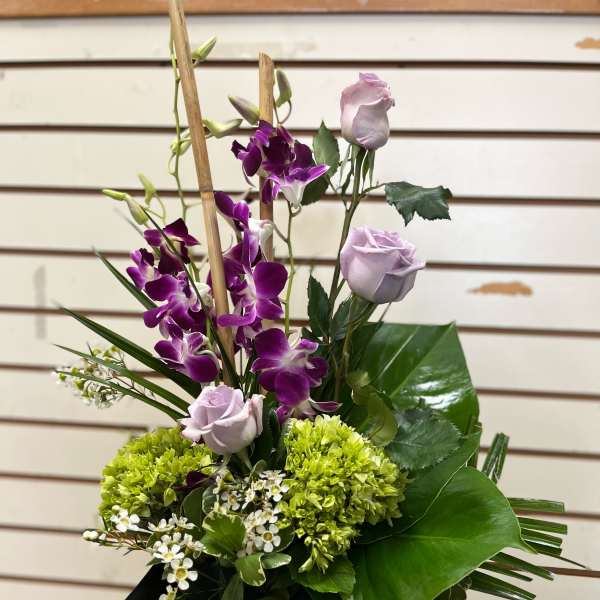 Purple orchids and pale lavender roses in a black vase