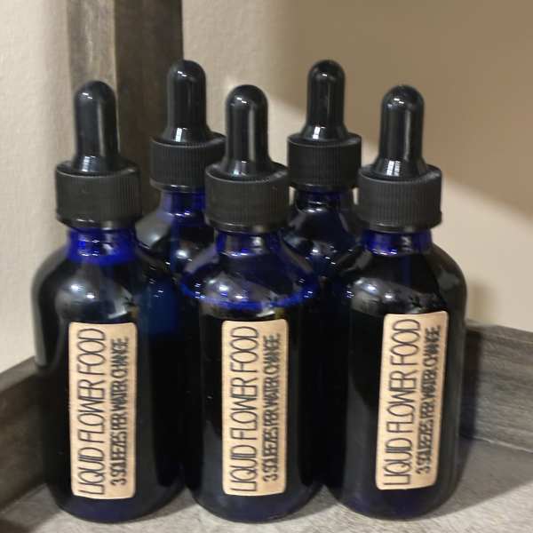 Five blue dropper bottles labeled liquid flower food