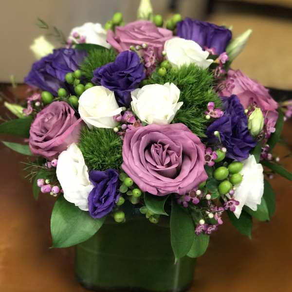 Bouquet of pink, purple, and white roses in a square vase