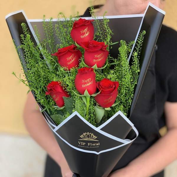 Bouquet of red roses wrapped in black paper with a birthday message