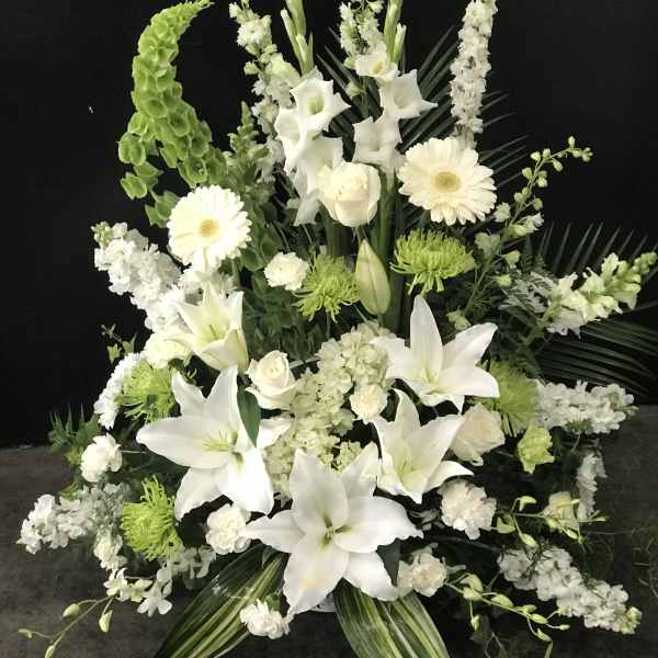 Large white floral arrangement with lilies, roses, and gerbera daisies