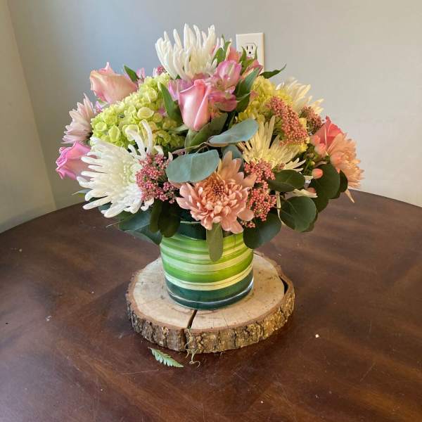 Mixed bouquet of pink, white, and peach flowers in a green striped vase