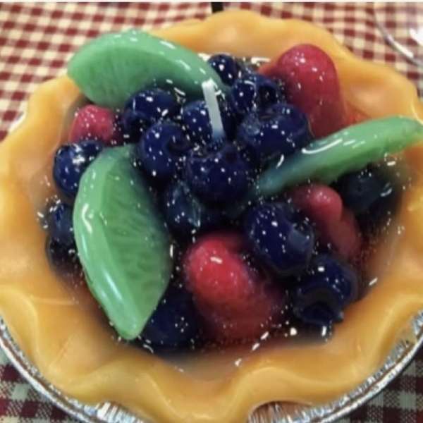 A fruit tart topped with blueberries, strawberries, and green fruit slices