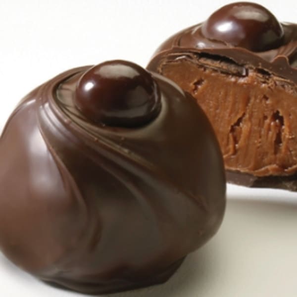 Two chocolate truffles on a white surface