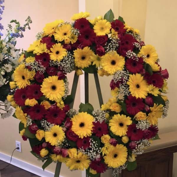 Large floral wreath on an easel with yellow and burgundy blooms