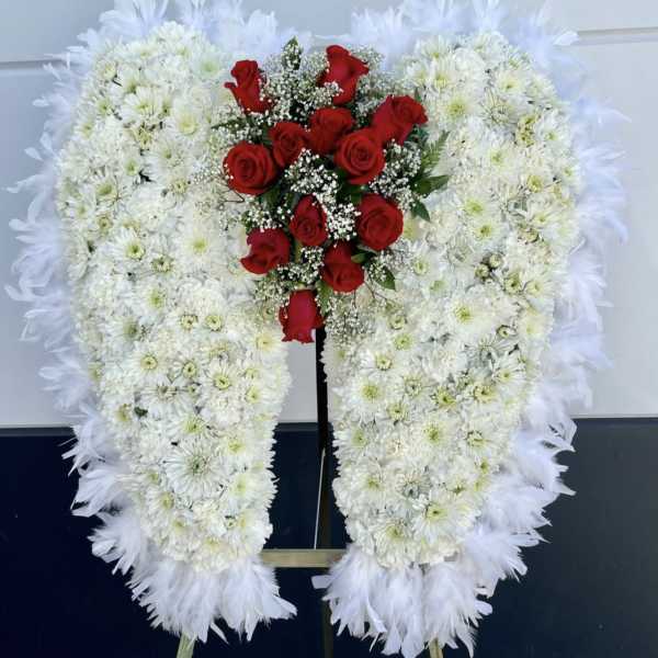 Heart-shaped white floral wreath with red roses on a stand