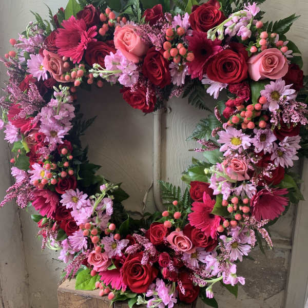 Heart-shaped floral wreath with red and pink roses and daisies