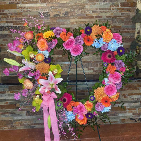 Large floral wreath on an easel with pink, orange, yellow, and blue blooms