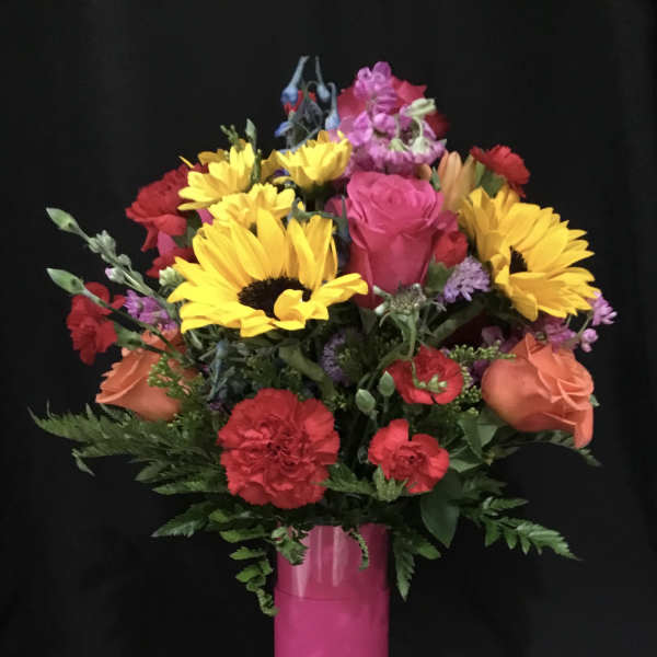 Colorful bouquet of sunflowers, roses, and carnations in a pink vase