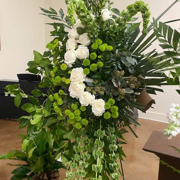 Tall green and white floral standing arrangement with roses and cascading foliage