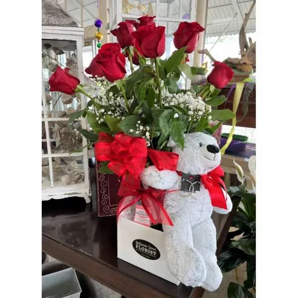 Red roses in a gift box with a teddy bear and ribbon