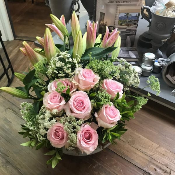 Pink roses and lilies arranged in a low round container