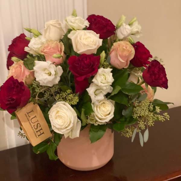 Bouquet of red, white, and blush roses in a pink vase