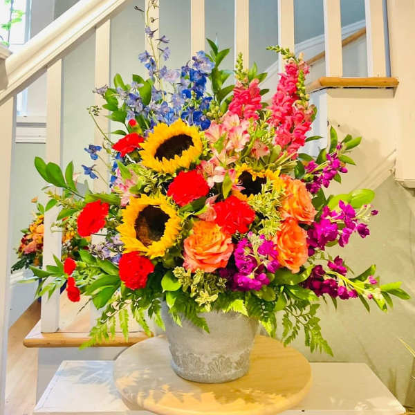 Colorful mixed flower arrangement in a gray vase on a round table