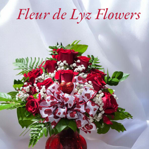 Red rose bouquet in a red vase with a heart ribbon