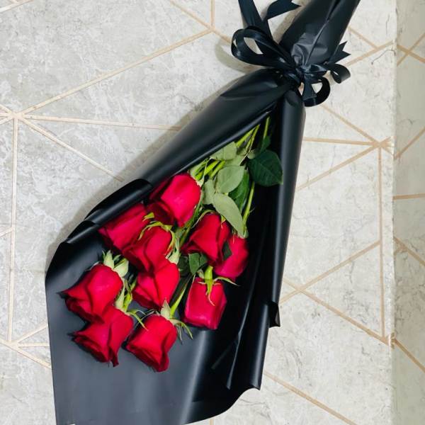Bouquet of red roses wrapped in black paper with a ribbon