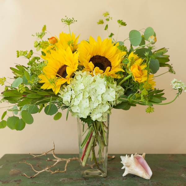 Sunflower bouquet with pale hydrangea in a clear glass vase