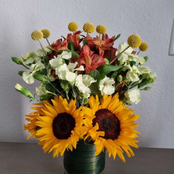Sunflowers, alstroemeria, and white carnations in a glass vase