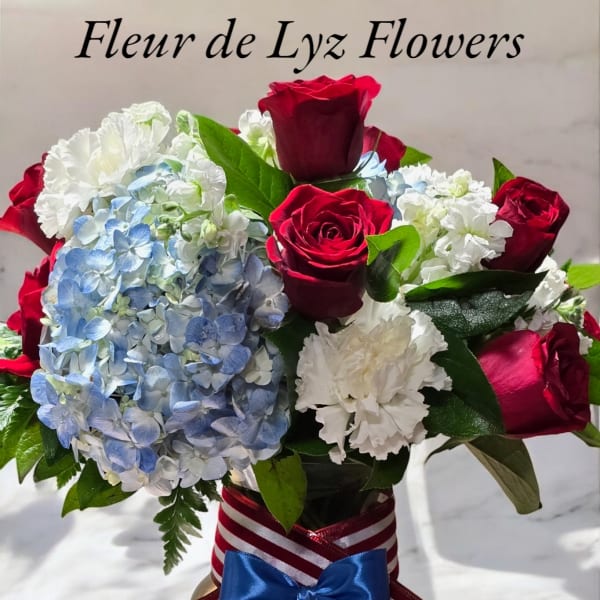 Bouquet of red roses, blue hydrangea, and white carnations in a glass vase
