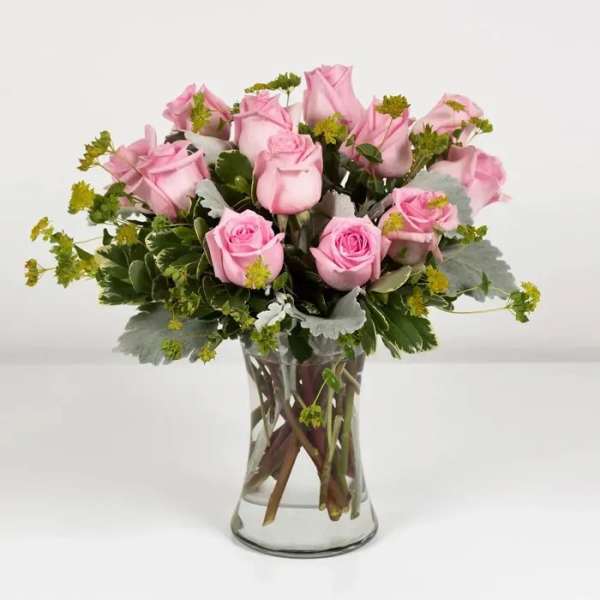 Pink roses arranged in a clear glass vase with greenery