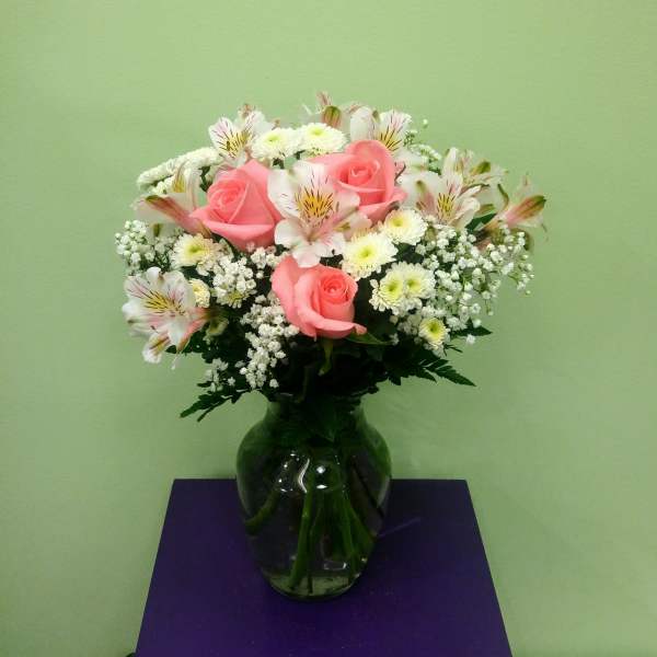 Pink roses and white flowers arranged in a glass vase