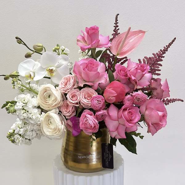 Pink roses and white orchids arranged in a gold vase