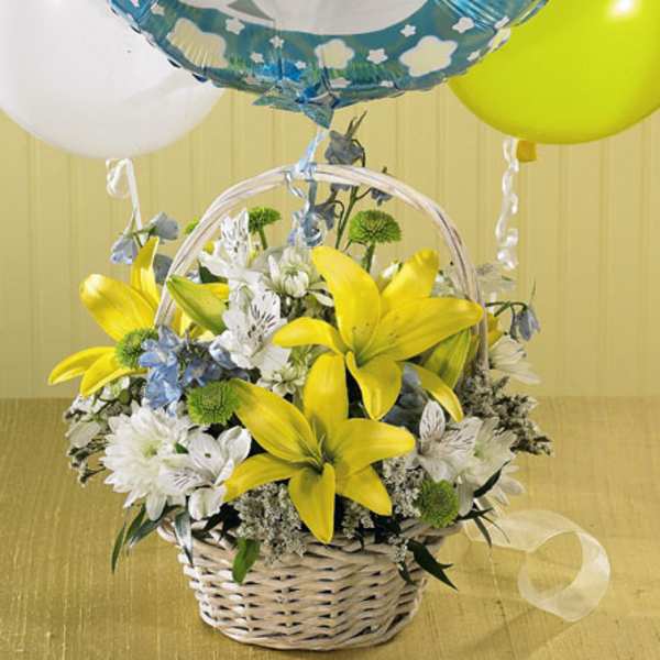 Basket of yellow lilies and white flowers with baby boy balloons