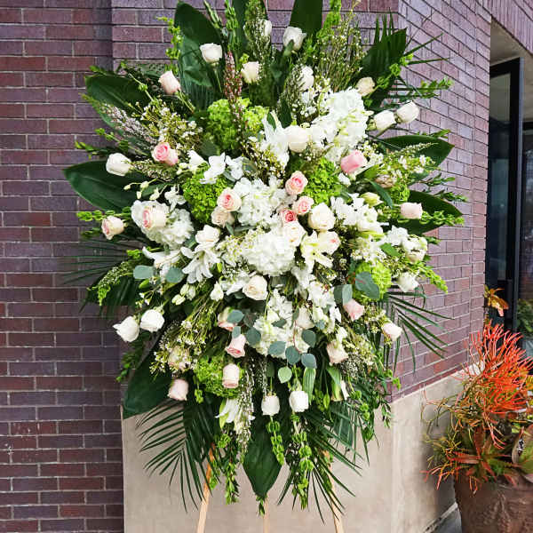 Tall standing spray of white hydrangeas and pale pink and white roses on a wooden easel