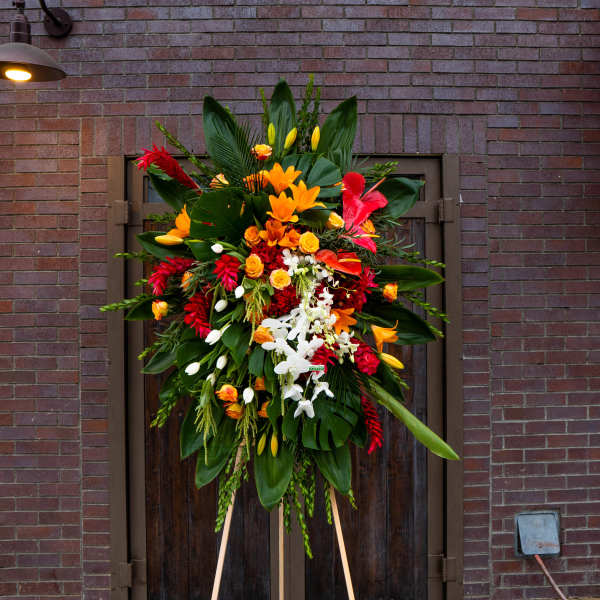 Large standing floral spray with red, orange, yellow, and white blooms