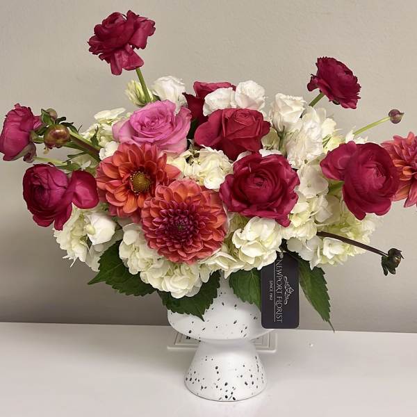Pink and white flower arrangement in a white pedestal vase